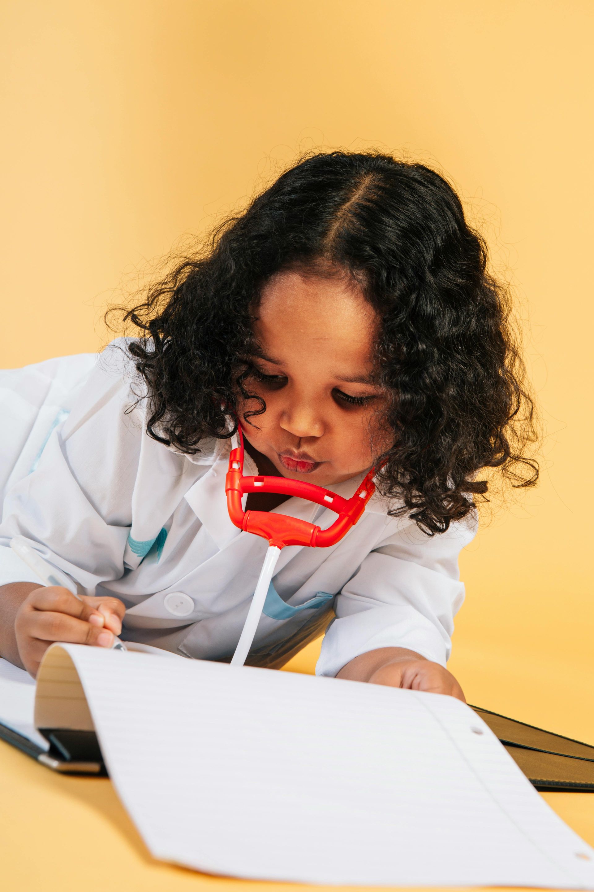 A little girl in a doctor costume is writing on a piece of paper.
