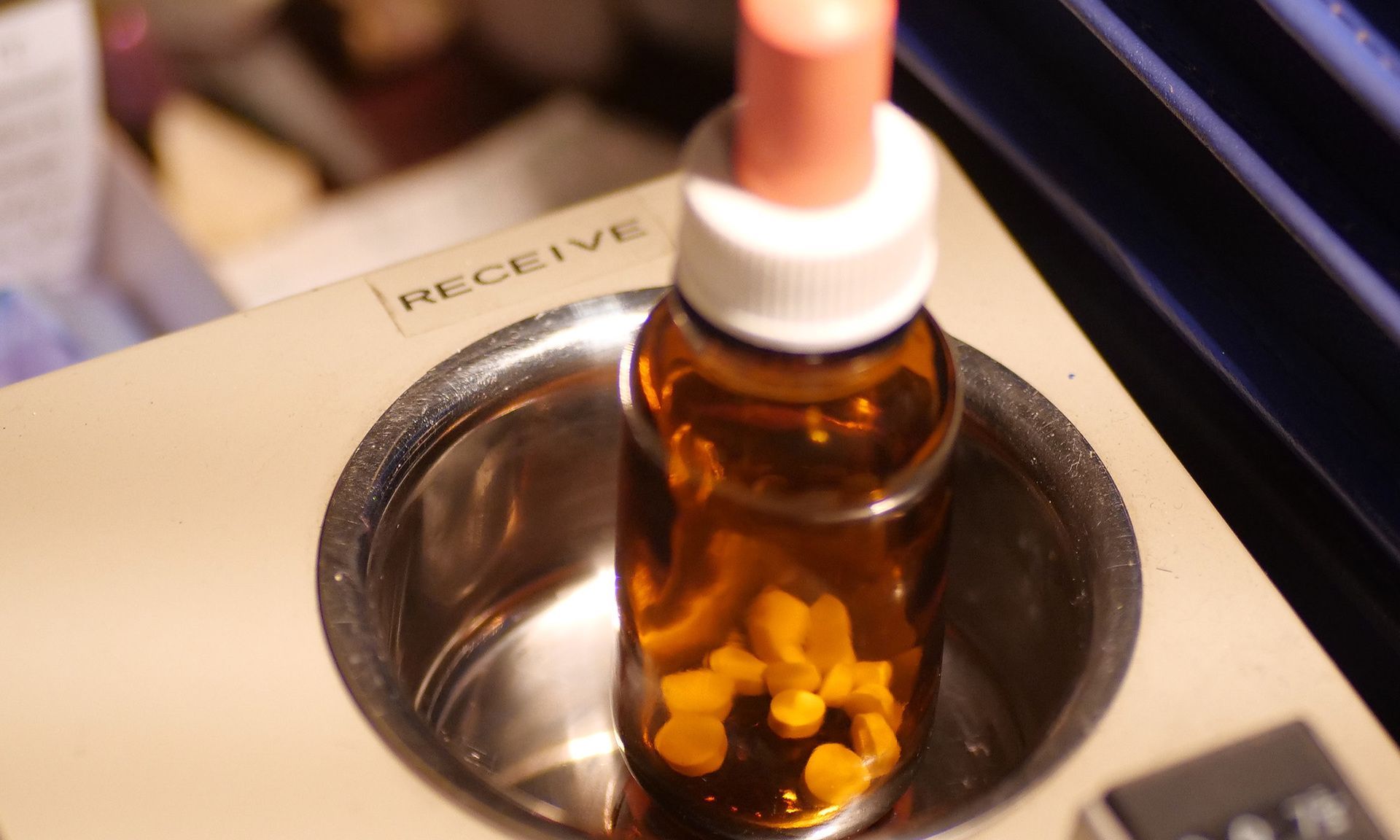 A bottle with a dropper in it sits in a metal container that says receive