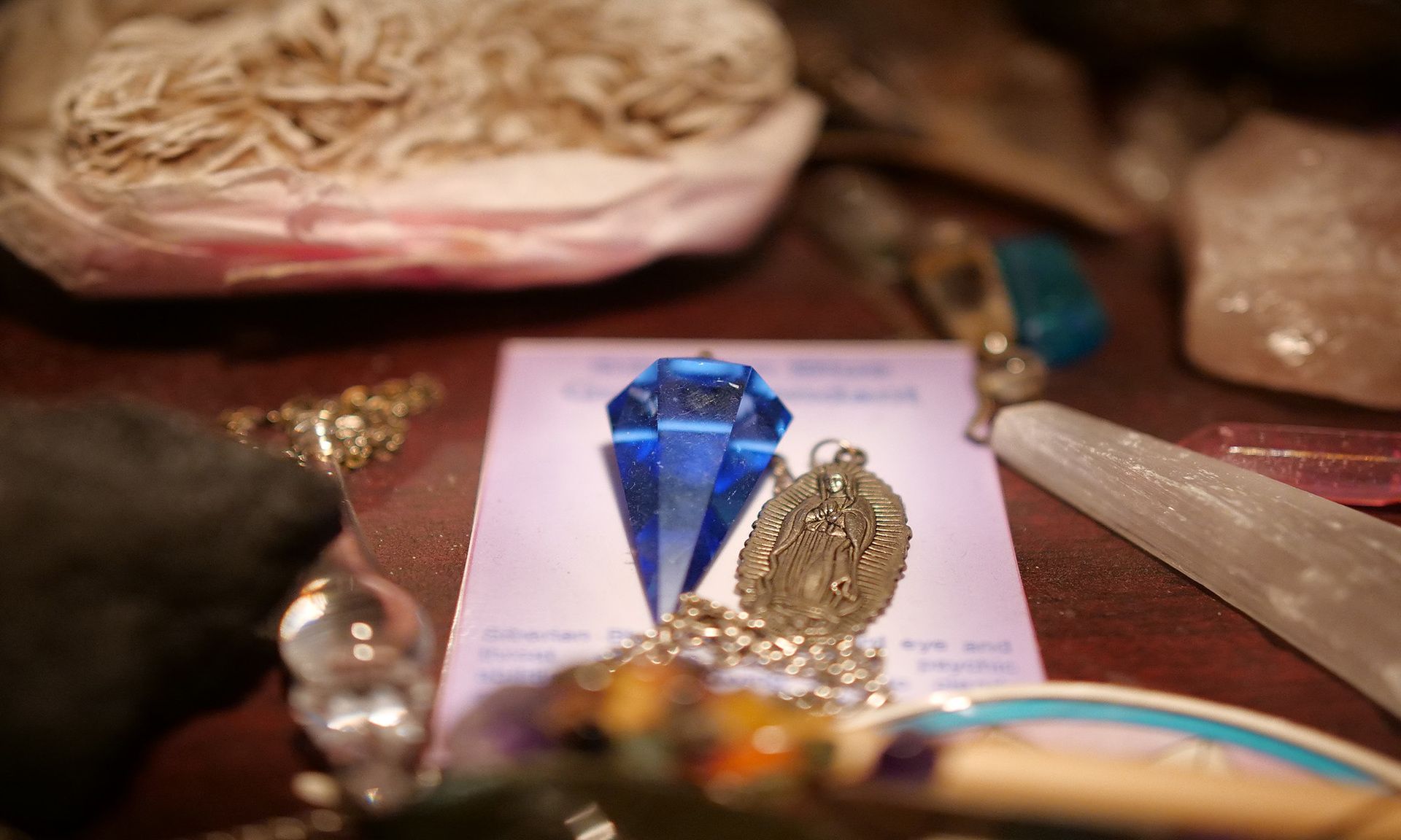 A blue pendulum is sitting on top of a purple card on a table.