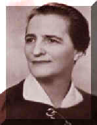 Woman in a dark jacket and white collared shirt, smiling slightly.