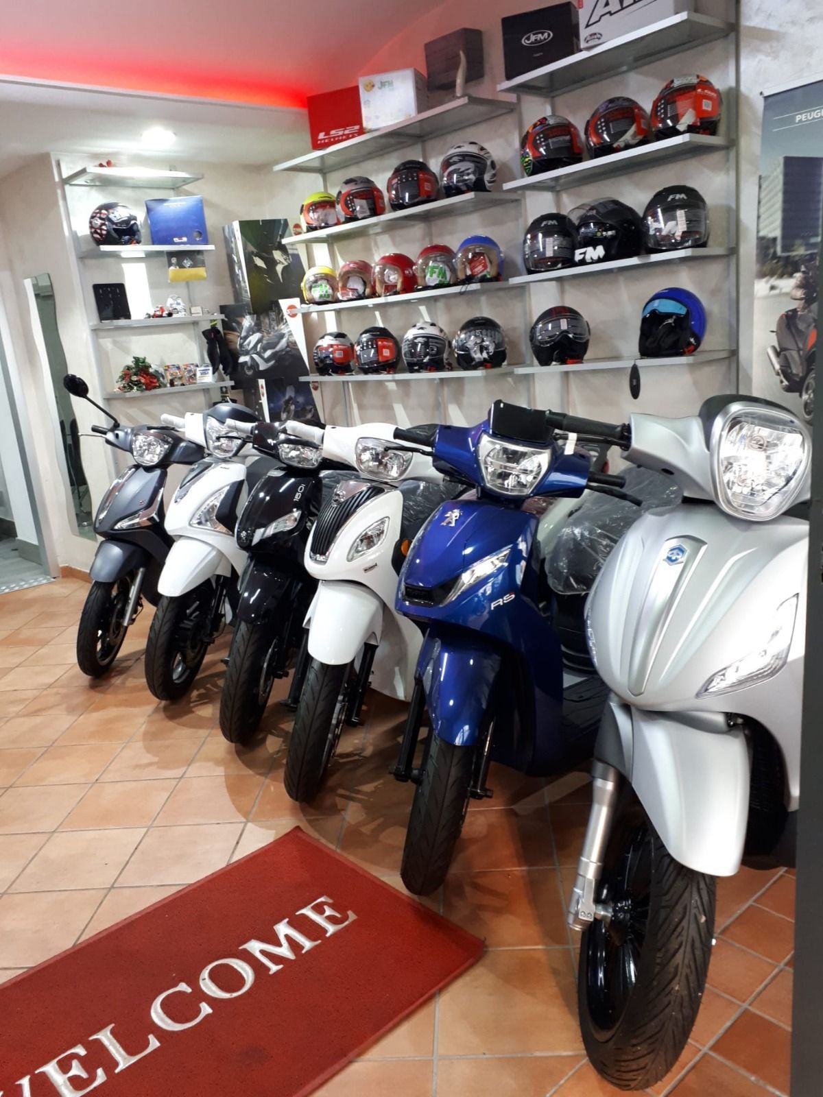 A row of motorcycles are parked in a showroom next to a welcome mat.