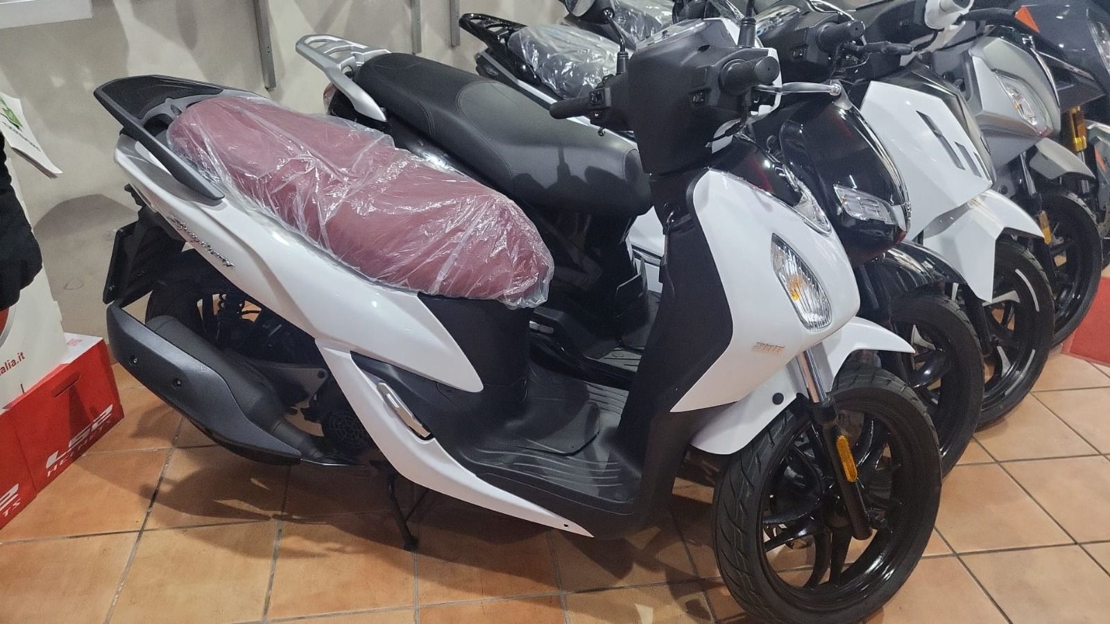 A row of scooters are parked in a showroom.