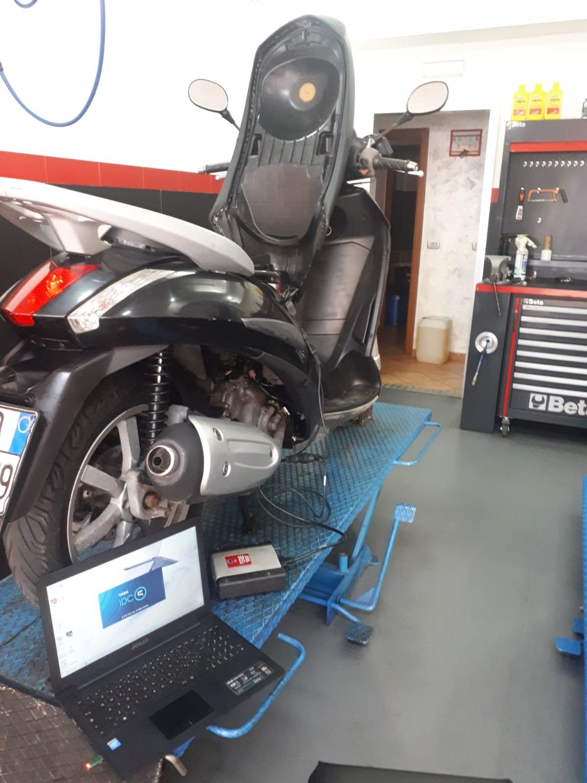 A scooter is sitting on a lift next to a laptop.