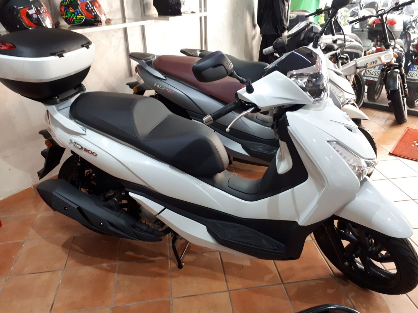 A white scooter is parked in a showroom next to other scooters.