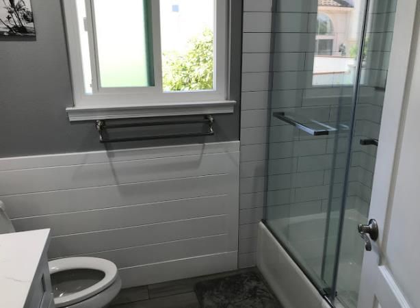 A bathroom with a toilet , sink , shower and window.