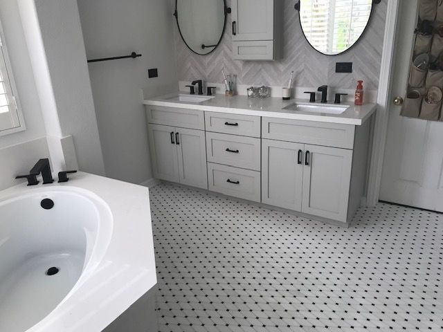 A bathroom with two sinks , two mirrors and a bathtub.