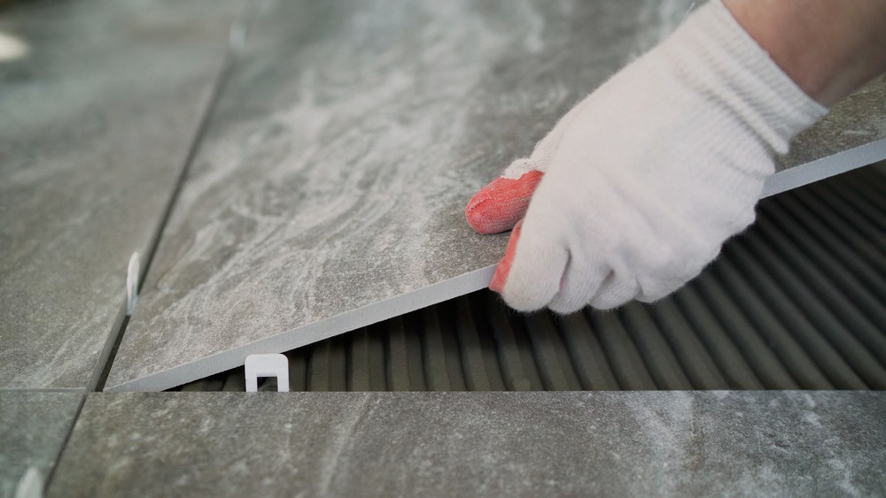 A person is laying a tile on the floor.