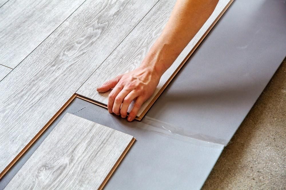 A person is installing a wooden floor in a room.