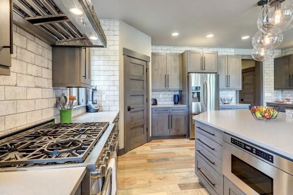 A kitchen with stainless steel appliances and gray cabinets.