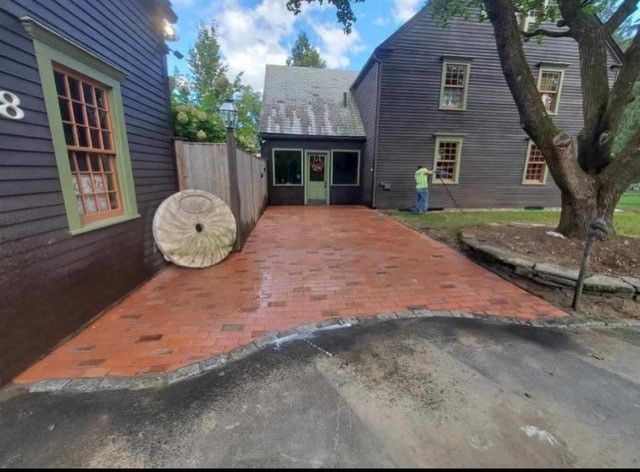 Brick paved driveway between dark buildings; one person working near the right side.