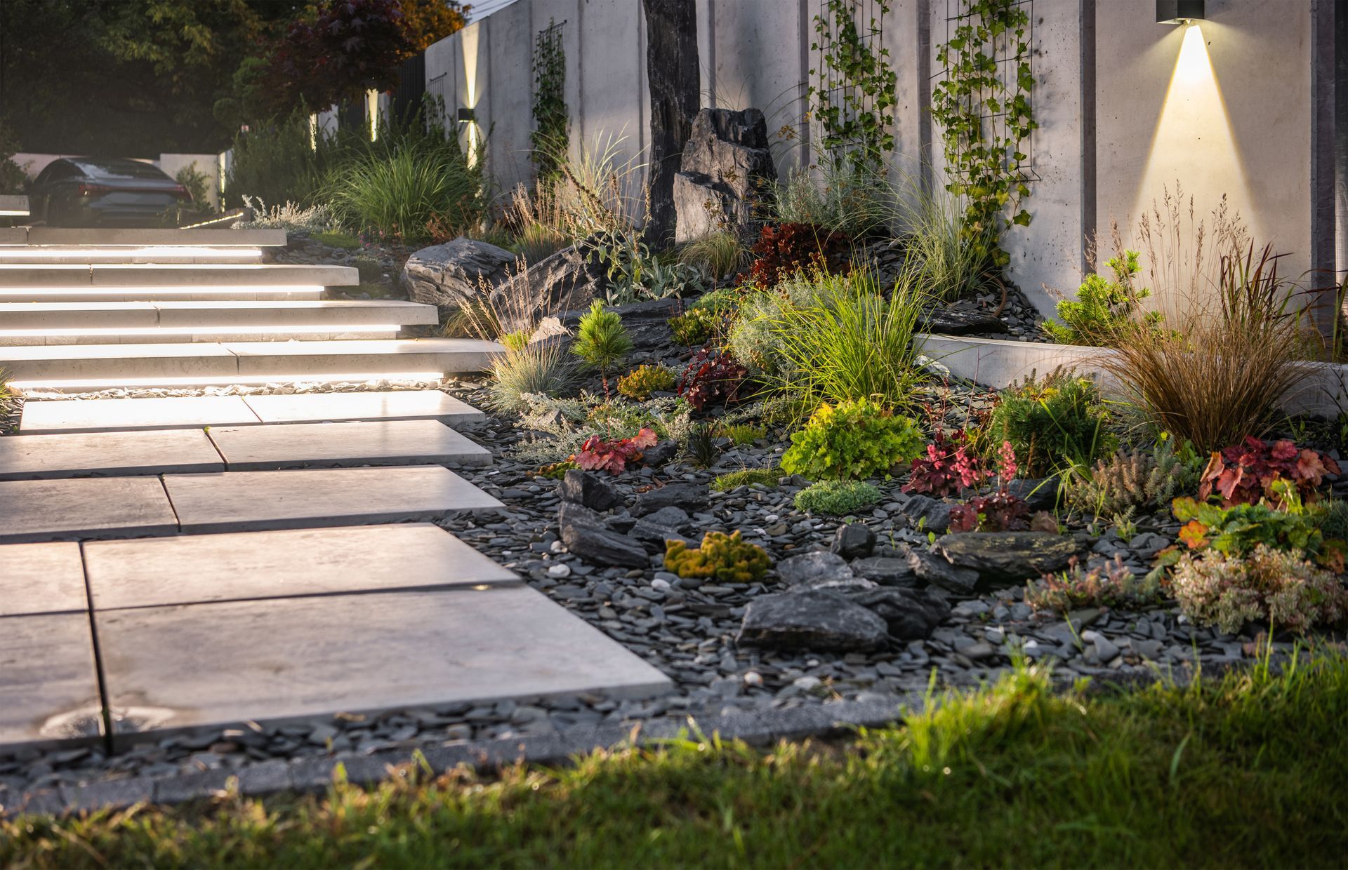 A garden with a lot of plants and rocks in front of a house.
