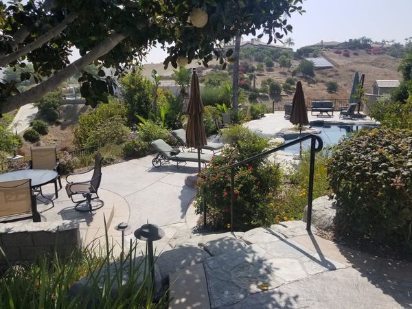 A patio with chairs and umbrellas and a pool in the background