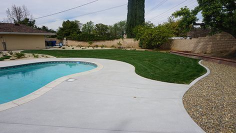 There is a swimming pool in the backyard of a house.