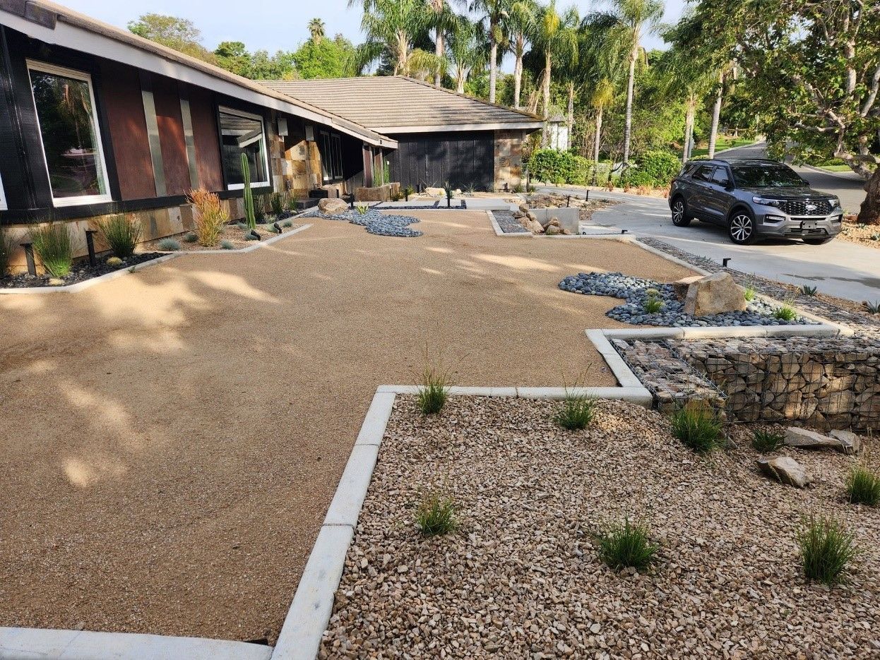 A car is parked in front of a house with a gravel driveway.