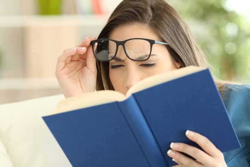woman squinting to read a book