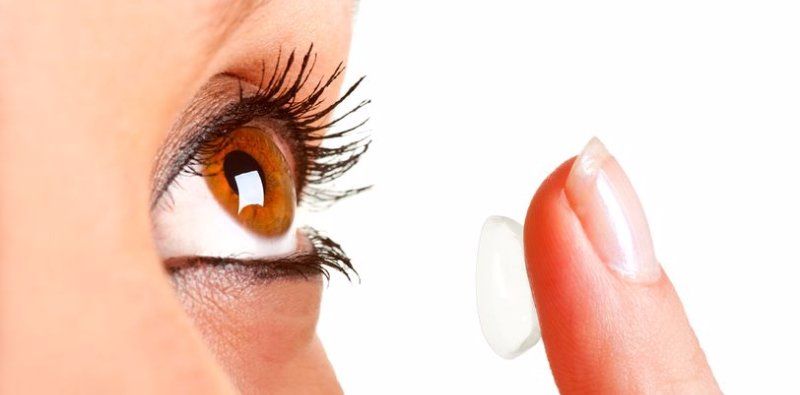 Woman placing contact lens into left eye