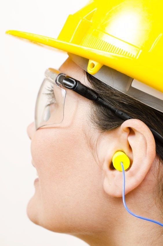 A woman wearing ear plugs, a hard hat and safety glasses