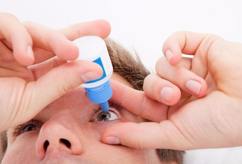 photo of a man using eye drops