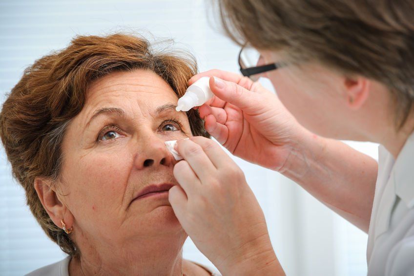 optometrist putting eye drops in patient's eye
