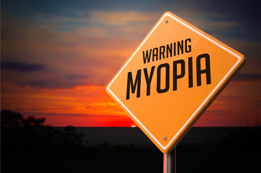 A warning sign for myopia with a sunset in the background