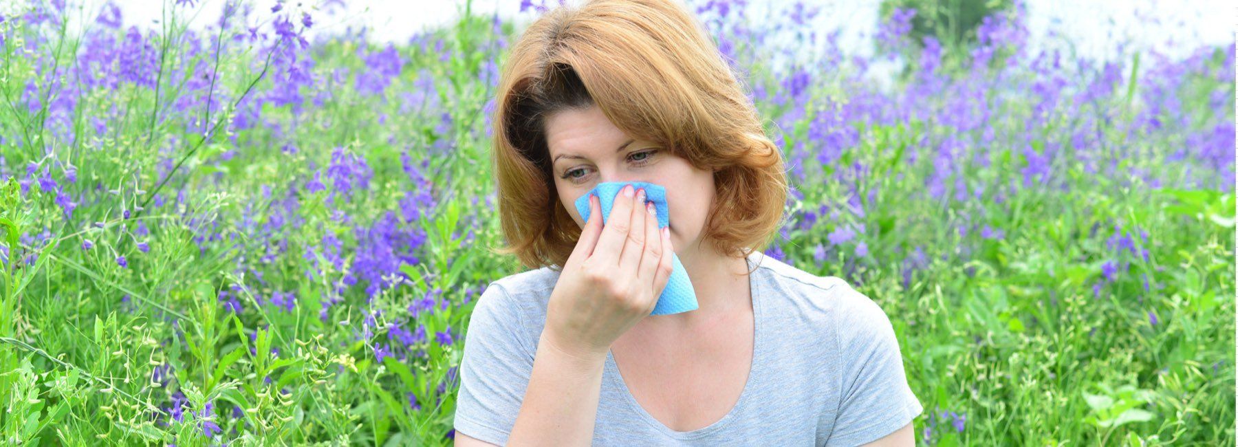 Woman blowing nose in a field of flowers