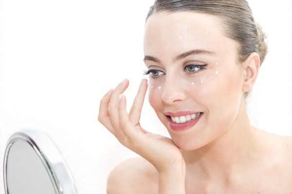 woman applying sunscreen around eyes