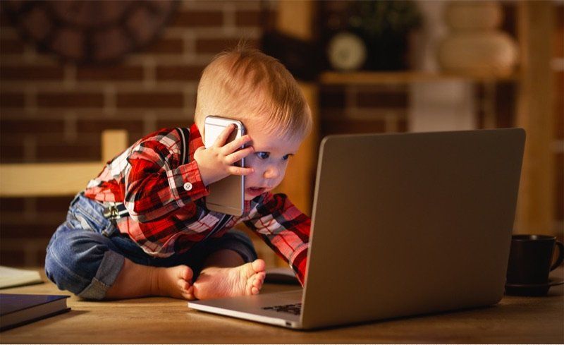 male toddler with phone and laptop computer