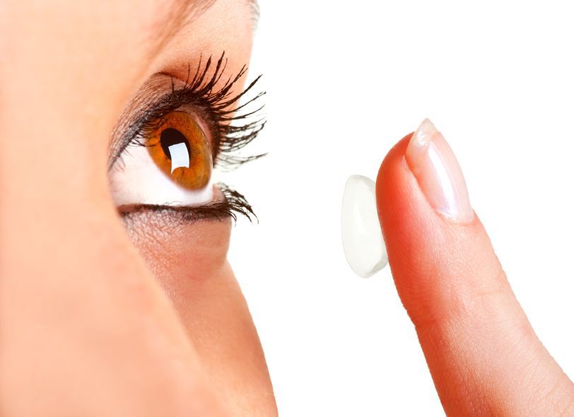 woman applying prescription contact lens to left eye