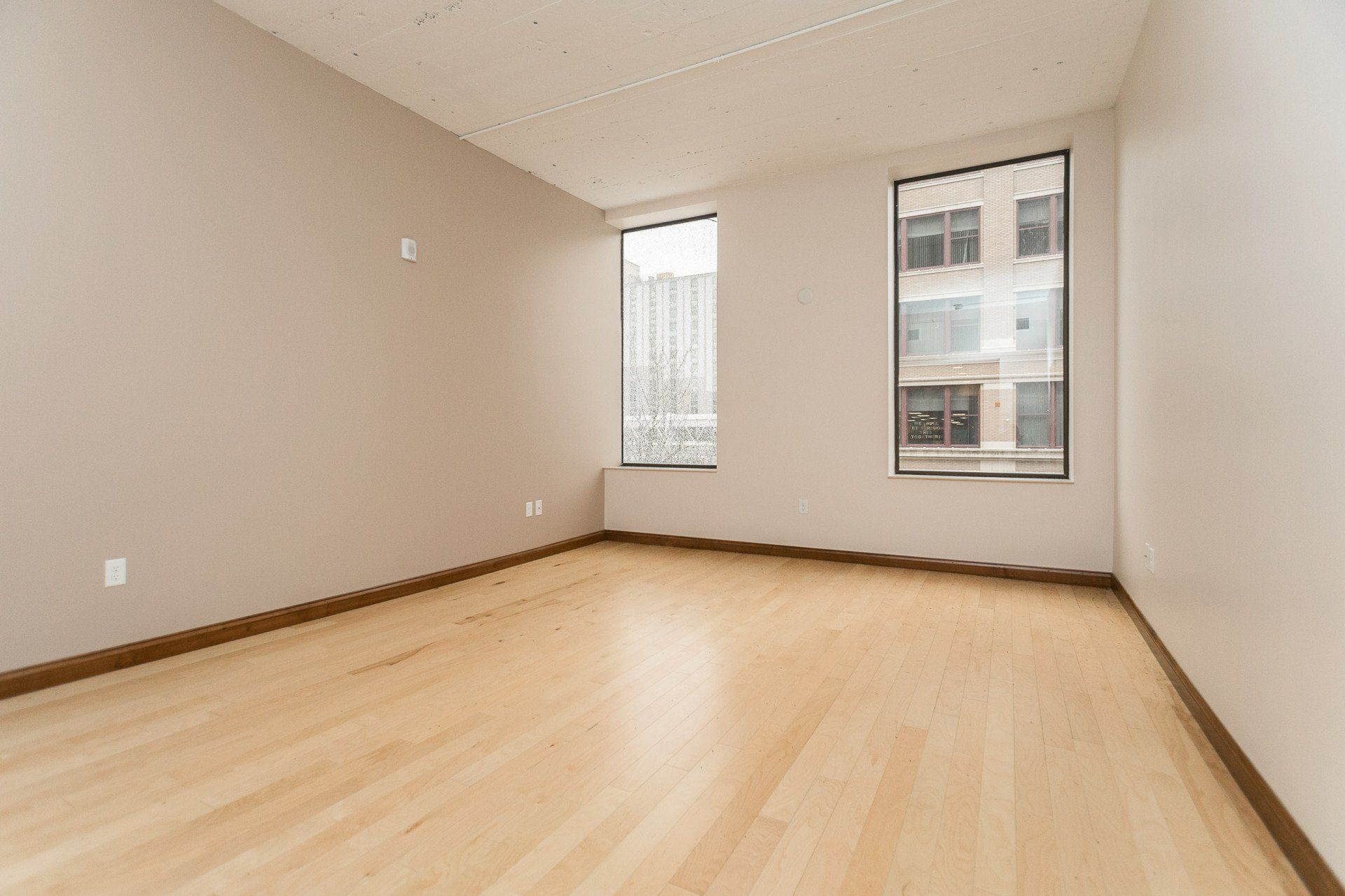 Interior with hardwood flooring, two large windows in background