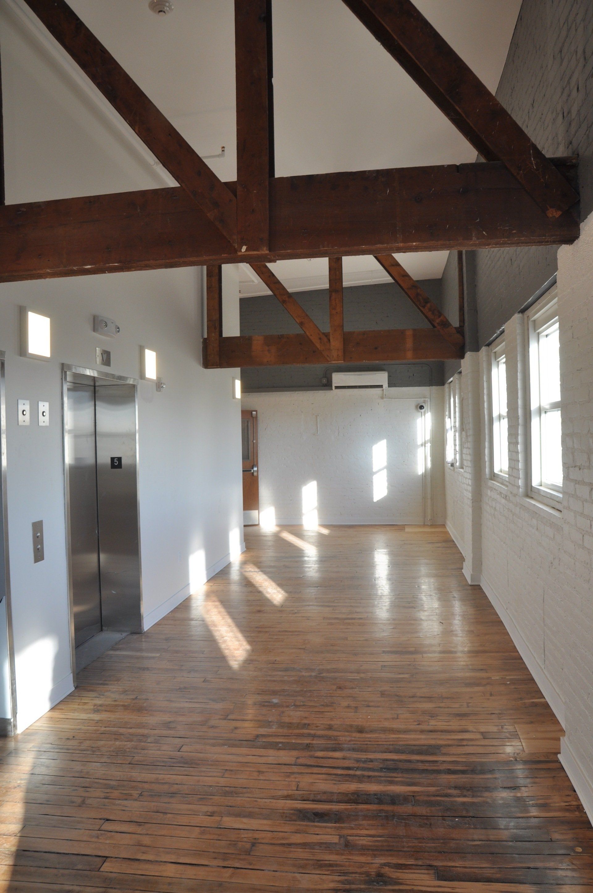 Interior of hallway with elevator access and wooden beams overhead