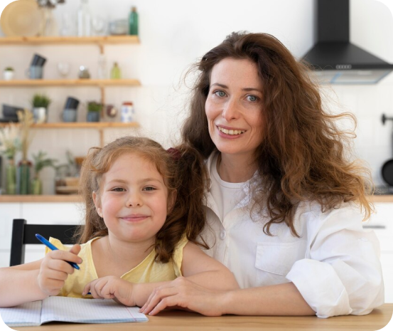 A woman and a little girl are sitting at a table doing their homework.