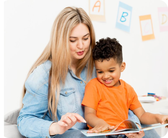 A woman is reading a book to a young boy.