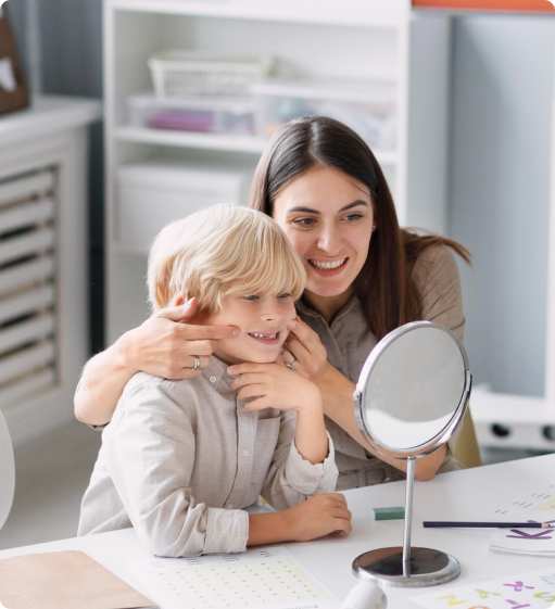 A woman is looking at her son 's face in a mirror