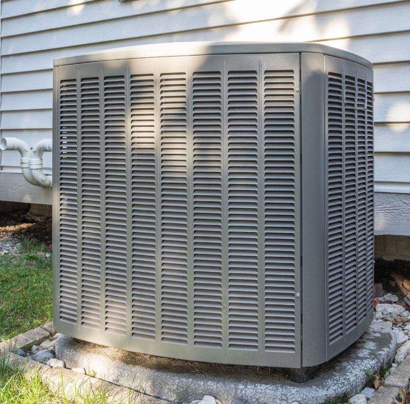 Gray air conditioning unit outside, near a house.