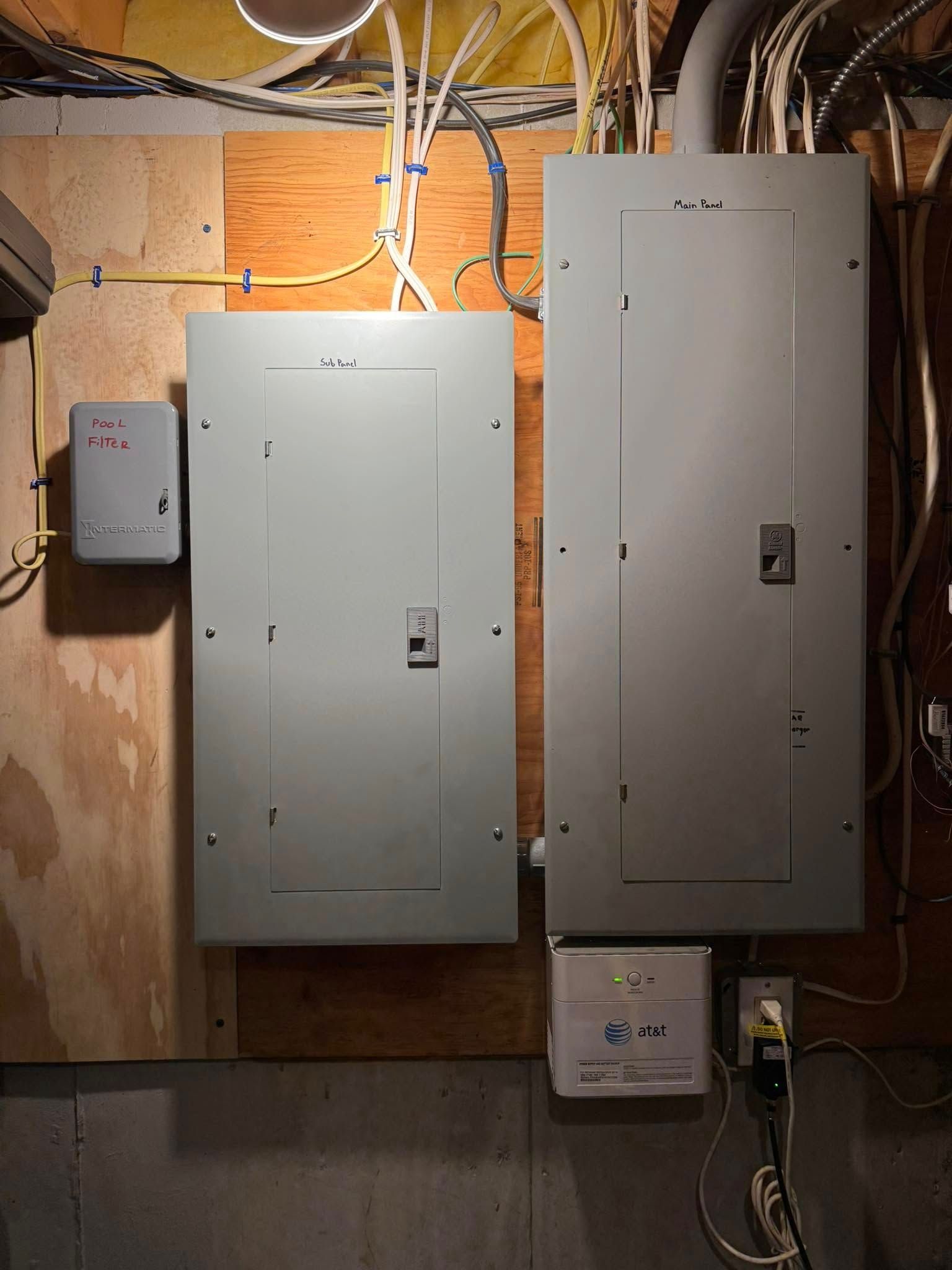 Electrical panels and devices on a wooden wall. Wires and conduit visible.