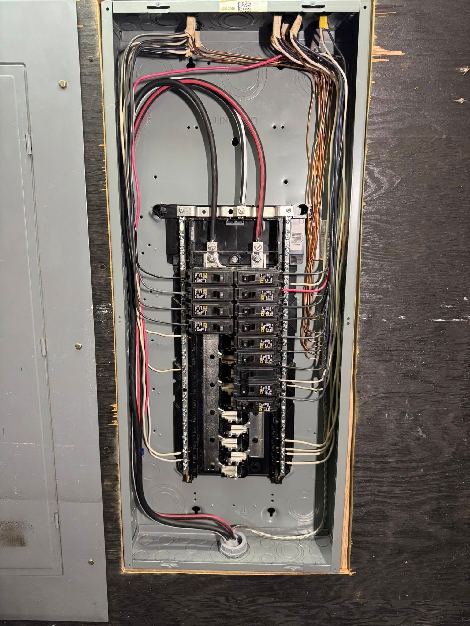 Open electrical panel with wires and circuit breakers.