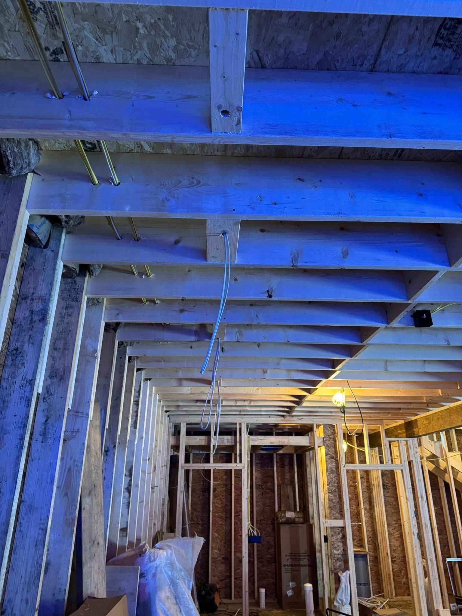 Interior framing of a building under construction, with exposed wooden beams and partially built walls.