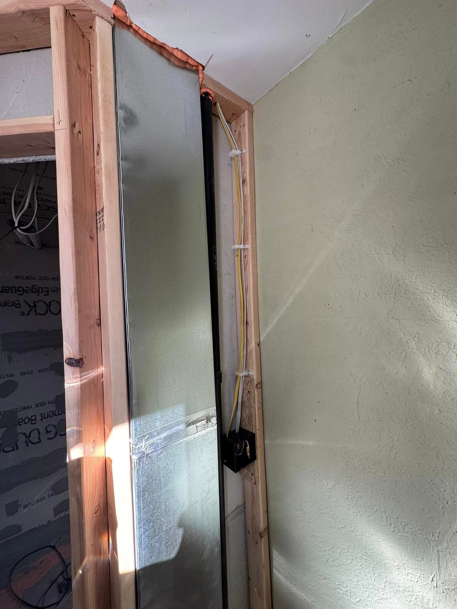 Wooden frame with metal sheeting and electrical wiring visible, partially completed interior.