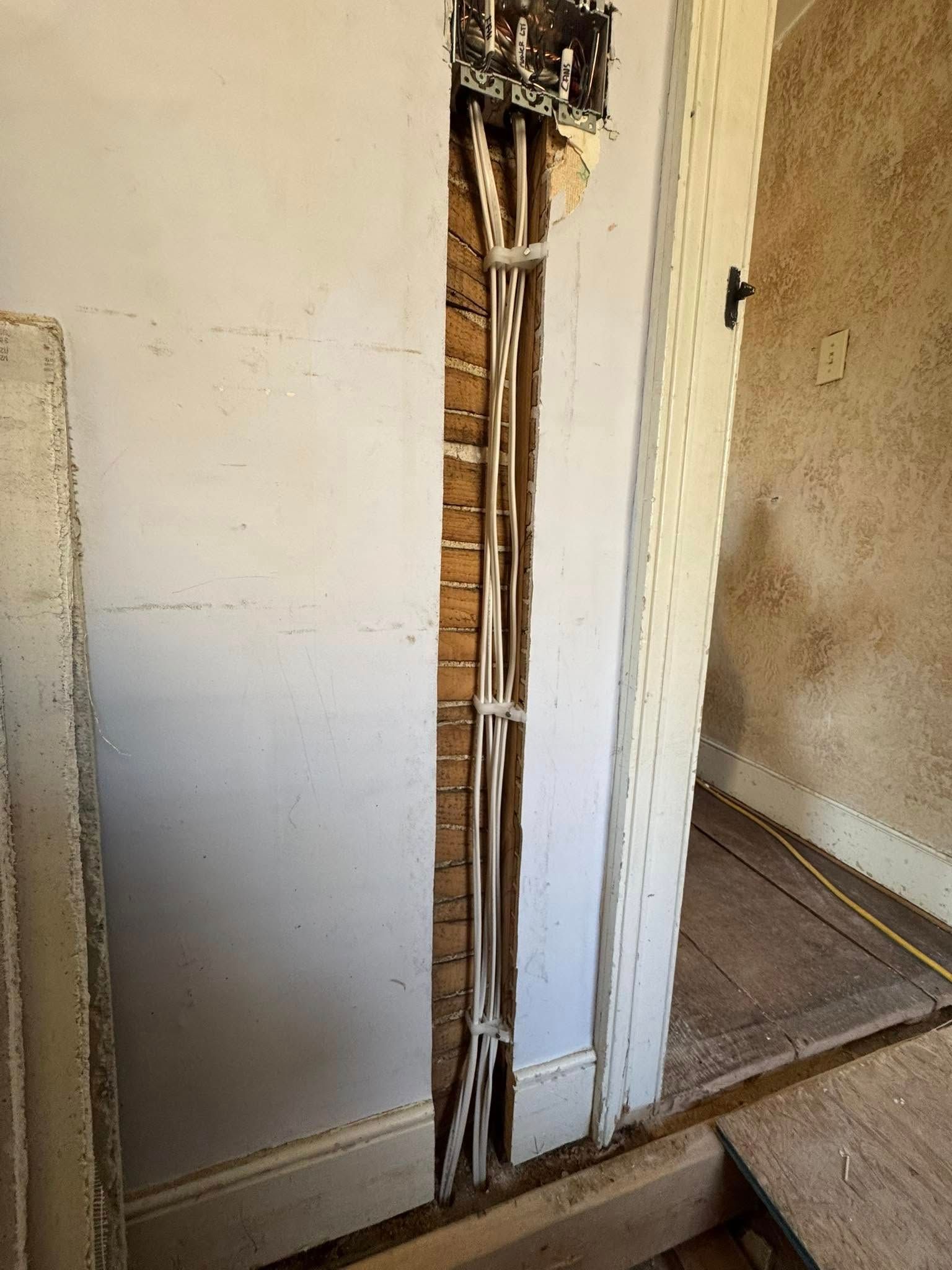 Exposed electrical wiring in a wall cavity, next to a doorway frame.