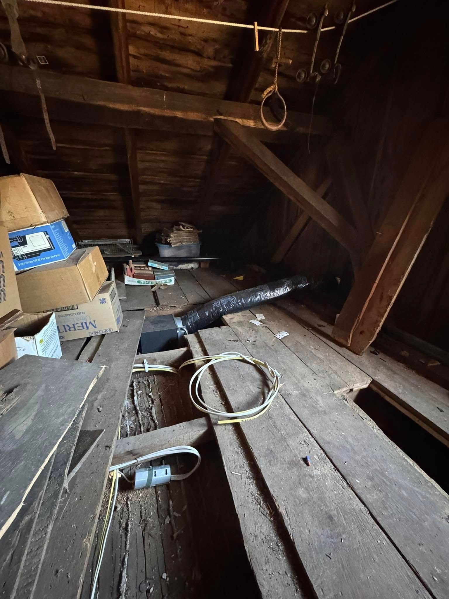 Attic with wooden beams, boxes, ductwork, and wiring.