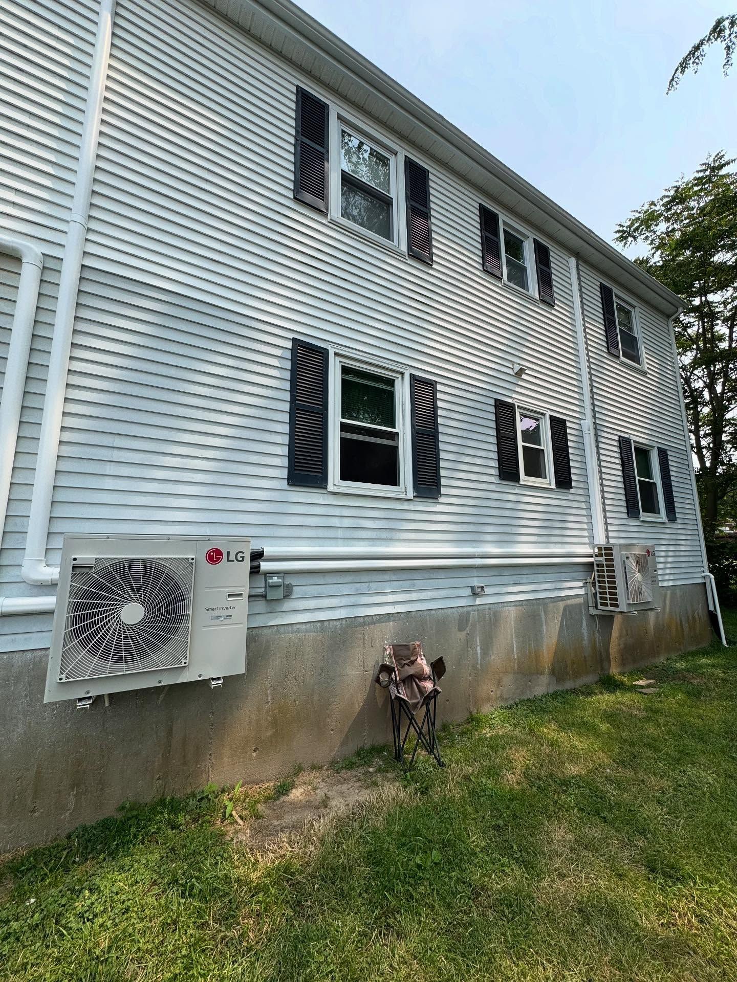 Exterior of a two-story white house with black shutters, an LG air conditioning unit, and green grass.