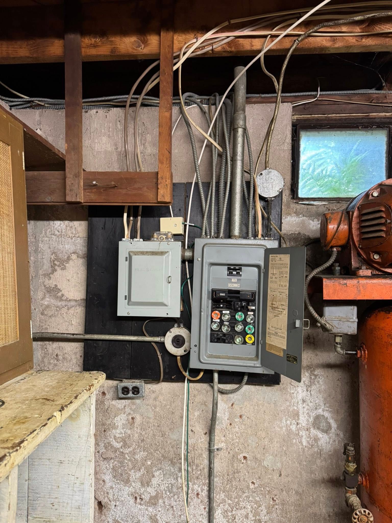 Electrical panels and wiring on a concrete wall in an industrial setting.