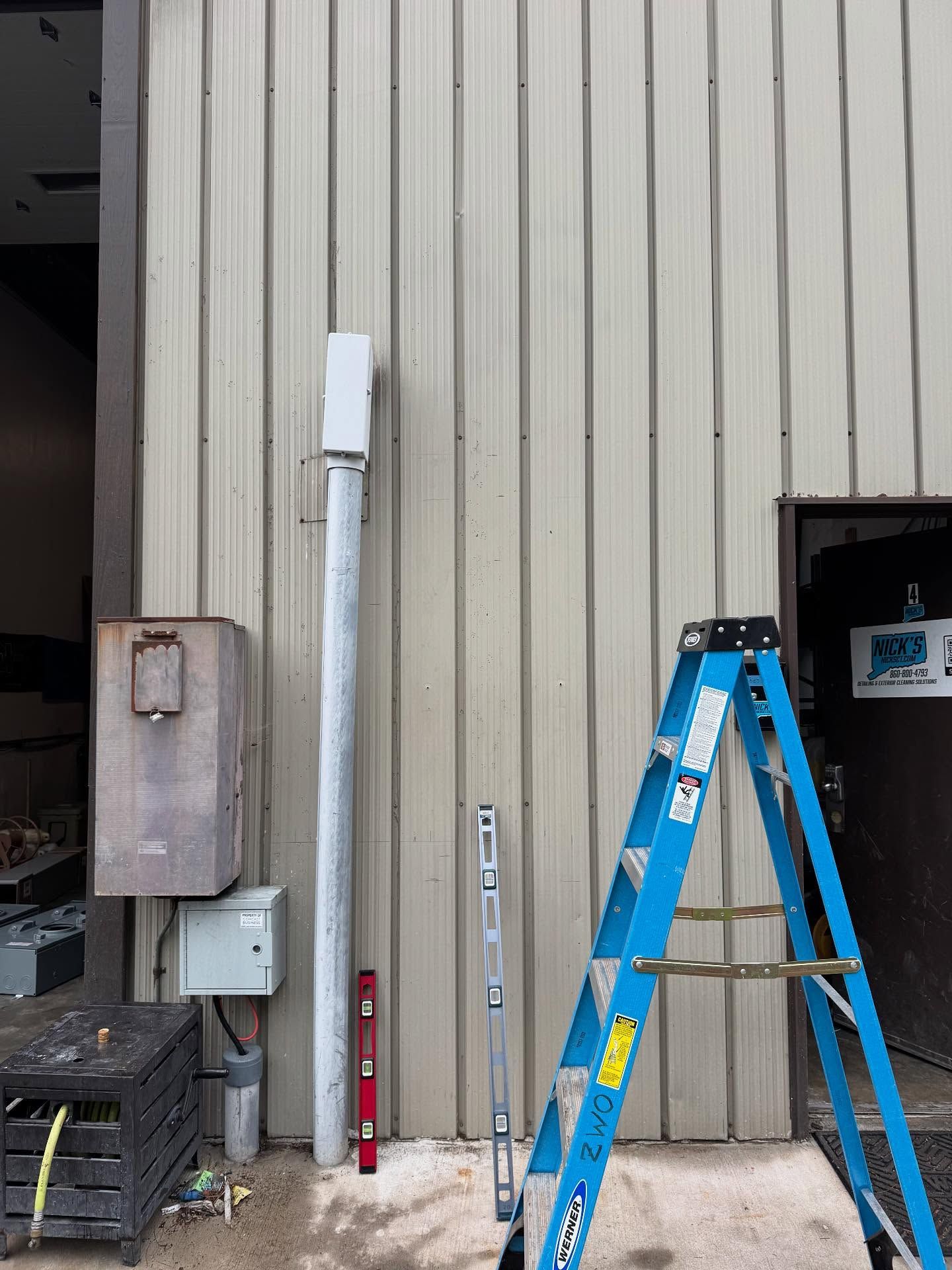 Exterior wall with equipment, ladder, and tools.