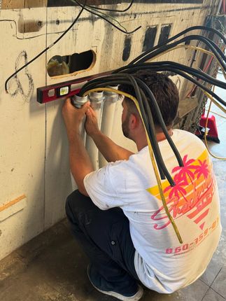 Electrical junction box in a wall, containing wires. Labels say