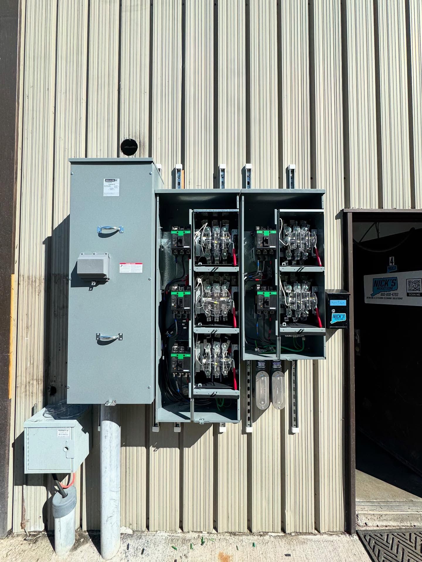 Electrical distribution boxes mounted on a corrugated metal wall.