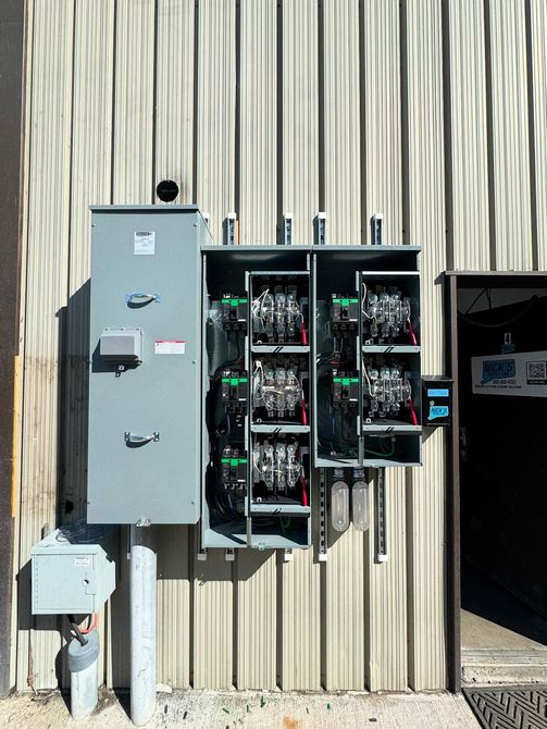 Electrical distribution boxes mounted on a corrugated metal wall.
