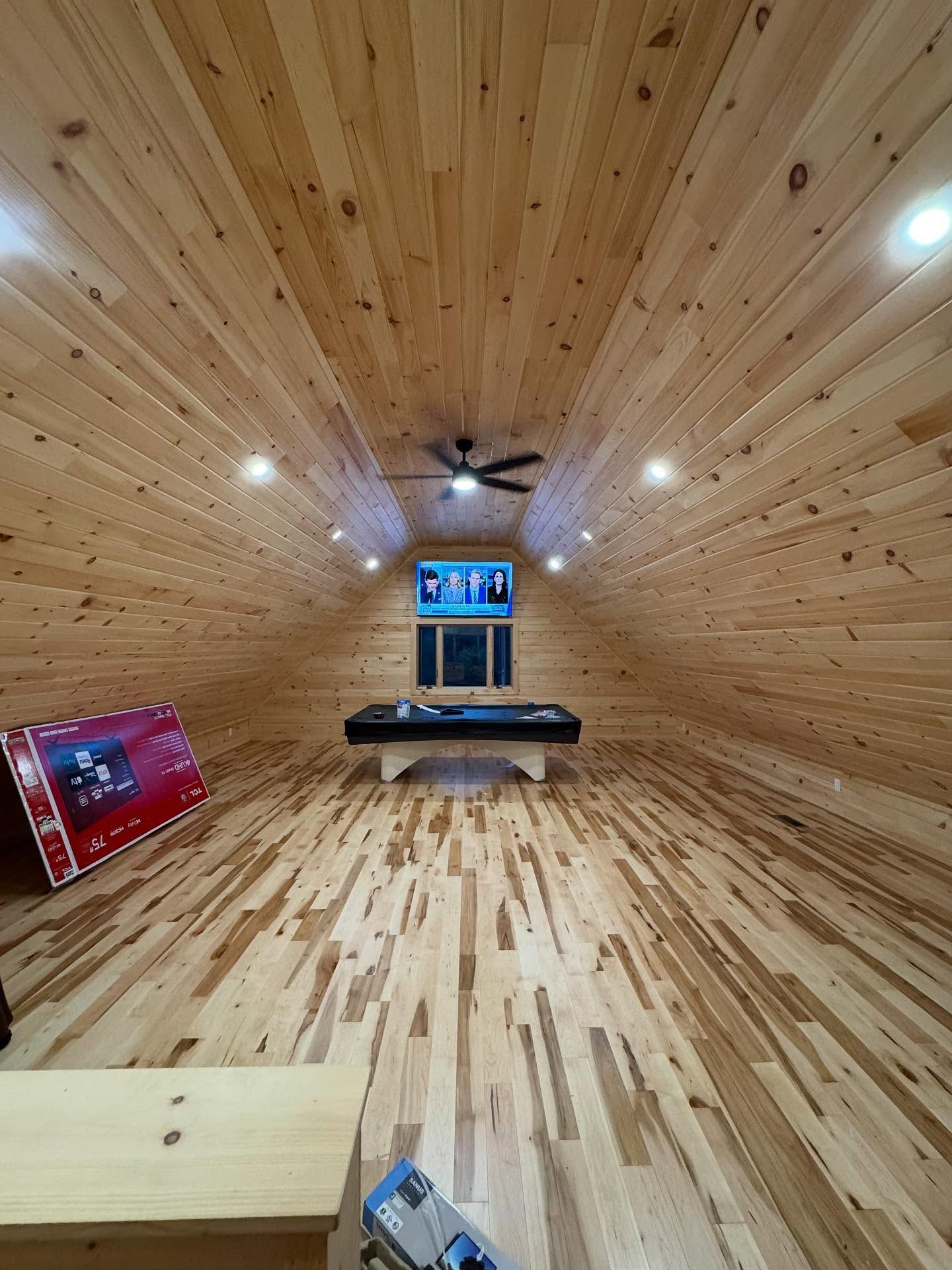 Wooden-paneled room with a pool table, ceiling fan, and recessed lights. A large box sits on the floor.