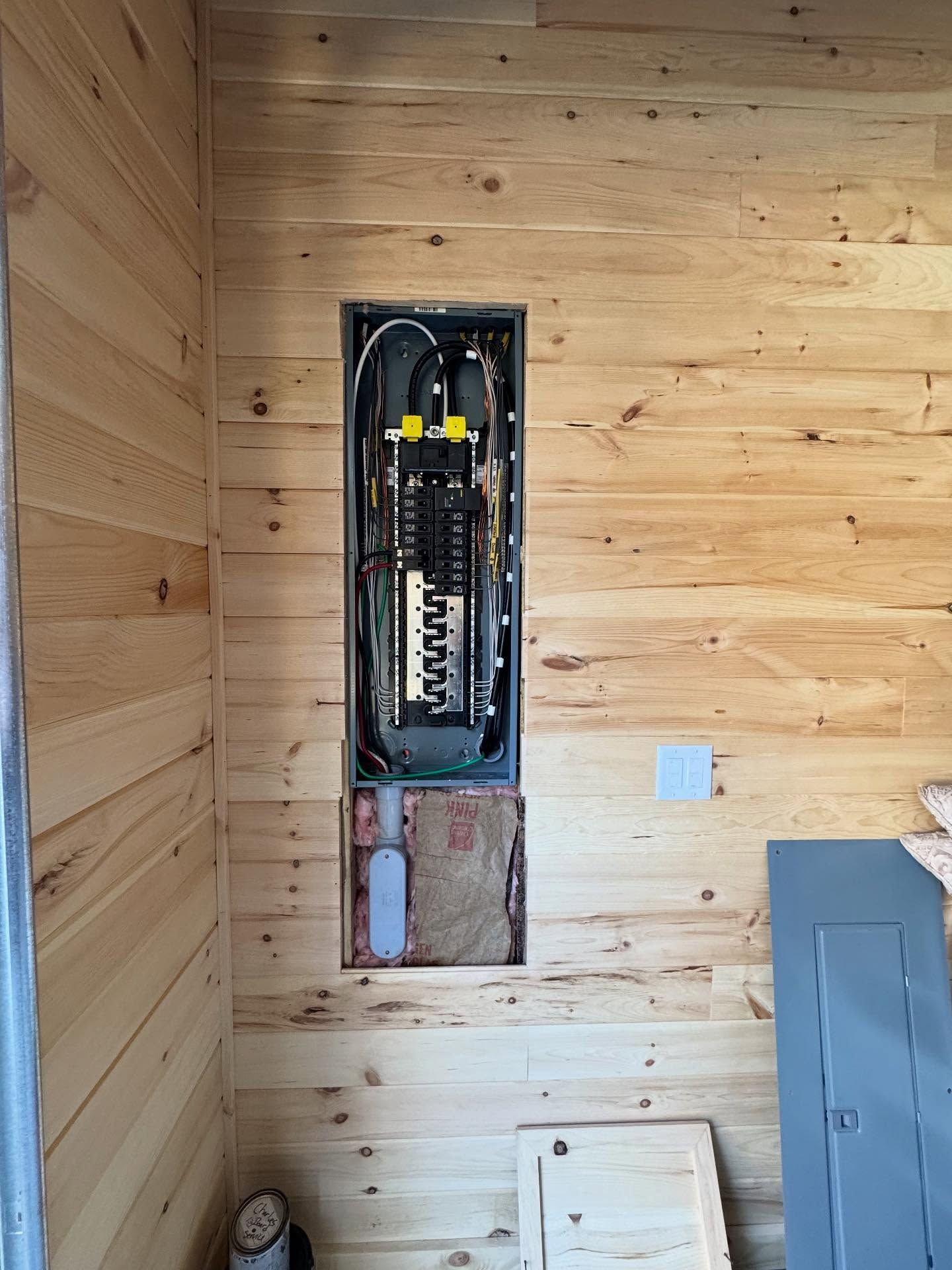 Electrical panel installed in a wooden wall; lower portion of wall cut away.