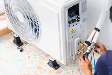 Person installing an air conditioner unit on a tiled patio.