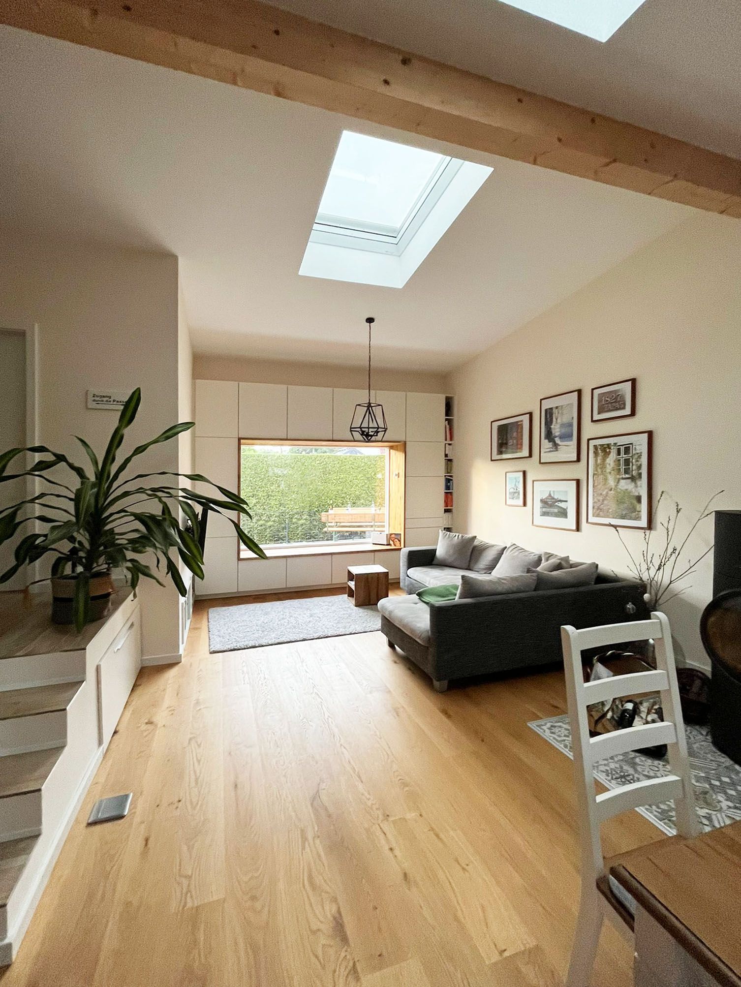 A living room with a couch , table and chairs and a skylight.